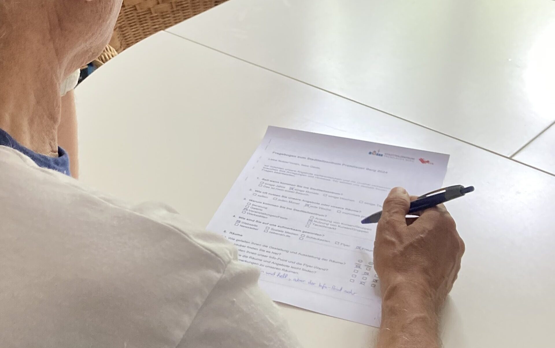 Eine ältere Damen füllt den Fragebogen des Stadtteilzentrums mit Kugelschreiber aus.